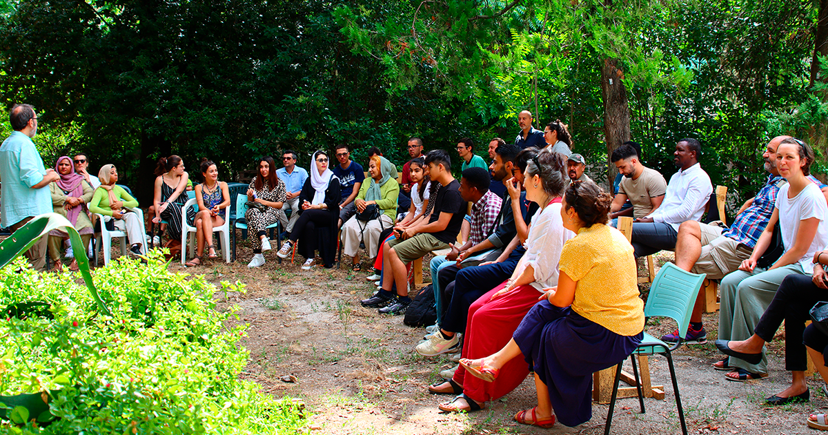 Un gruppo di persone sedute sotto gli alberi del parco Prato Giardino di Viterbo durante la consegna degli attestati dei corsi di formazione di Arci Solidarietà Viterbo SRL Impresa Sociale